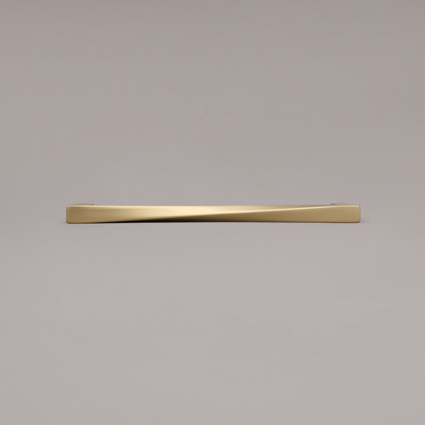 12" Twist appliance pull in Satin Brass laying on gray background