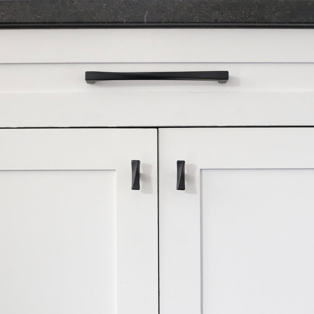 Twist matte black pull and knobs installed on white cabinet