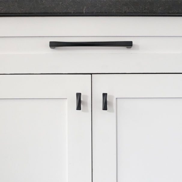 Twist matte black pull and knobs installed on white cabinet