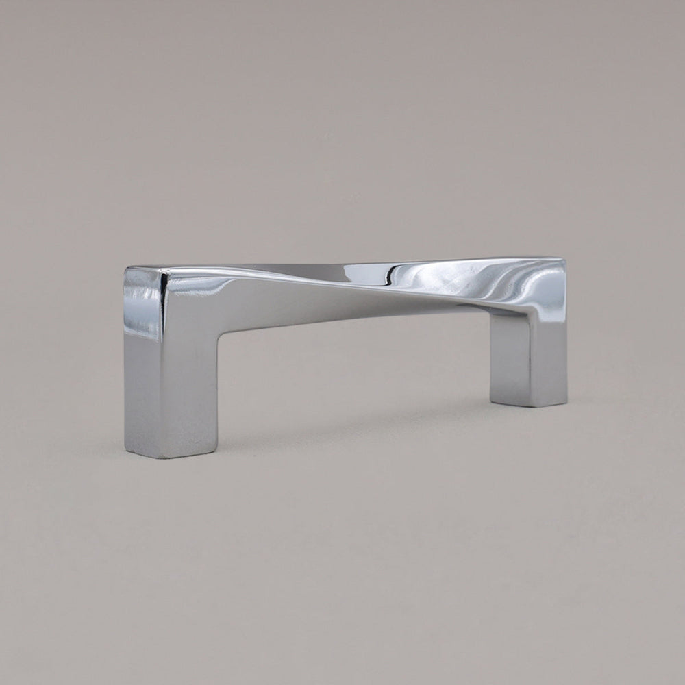 small polished chrome twist cabinet pull standing angled on gray background 