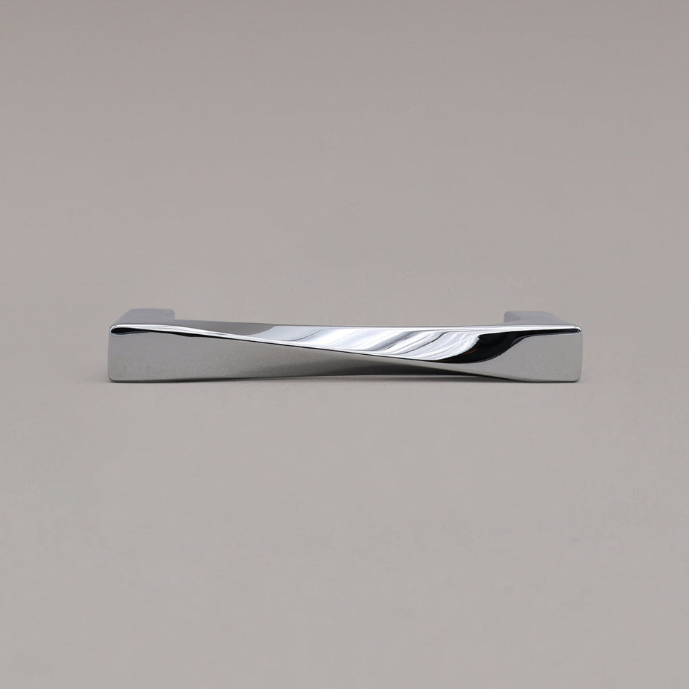 small polished chrome twist cabinet pull laying down on gray background