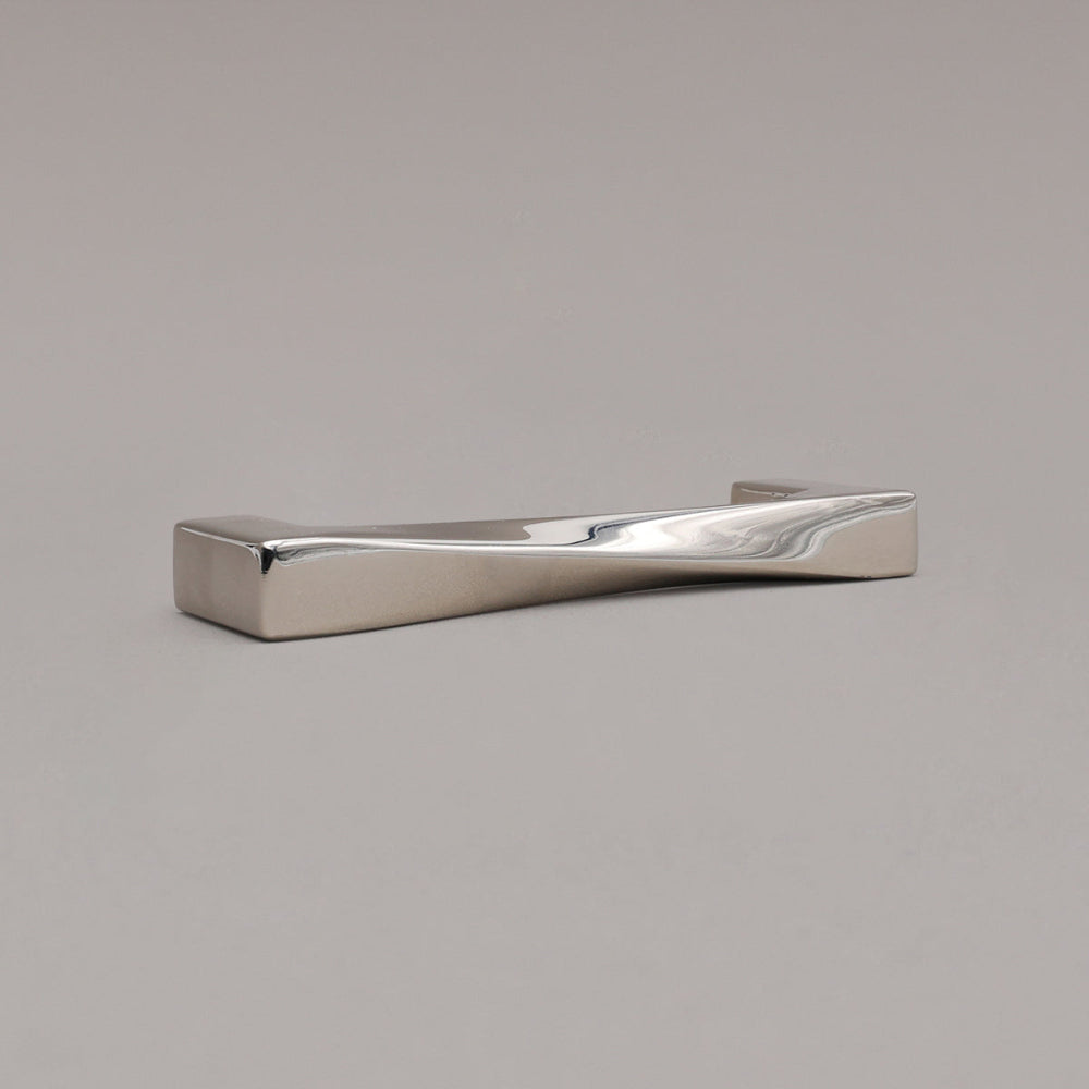 small twist polished nickel cabinet pull laying on gray background, angled
