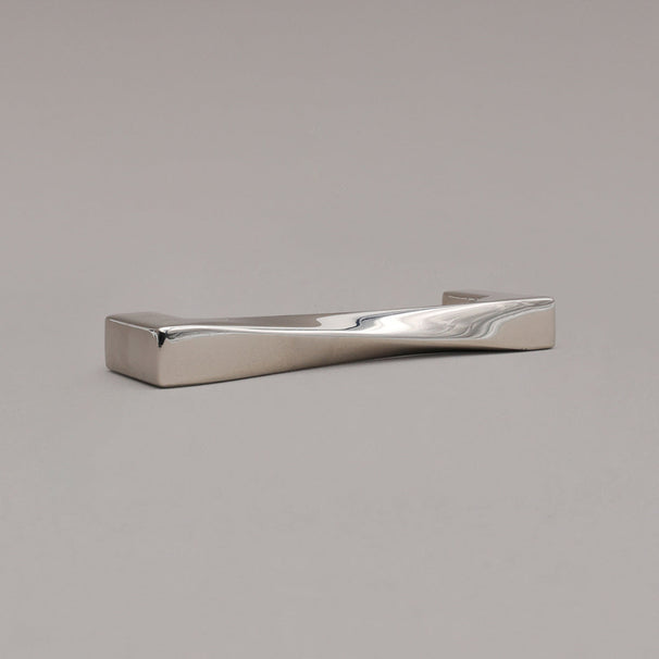 small twist polished nickel cabinet pull laying on gray background, angled