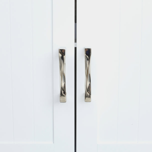 twist polished nickel cabinet pulls installed on white cabinet