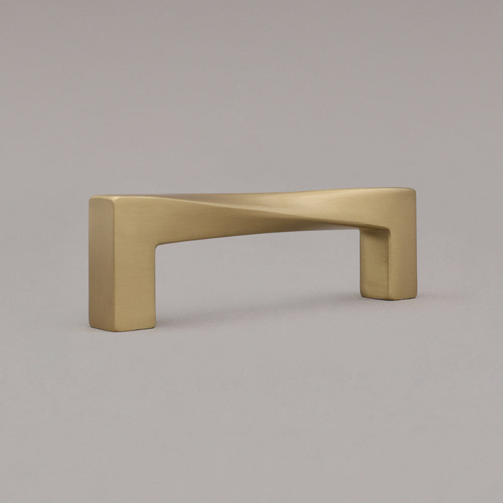 small twist satin brass gold pull standing on gray background, angled