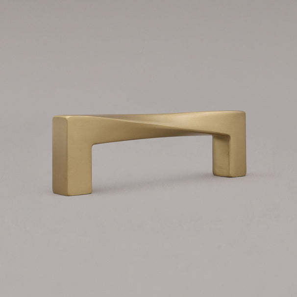 small twist satin brass gold pull standing on gray background, angled