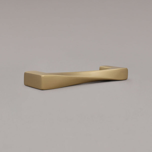small twist satin brass gold pull laying angled on gray background