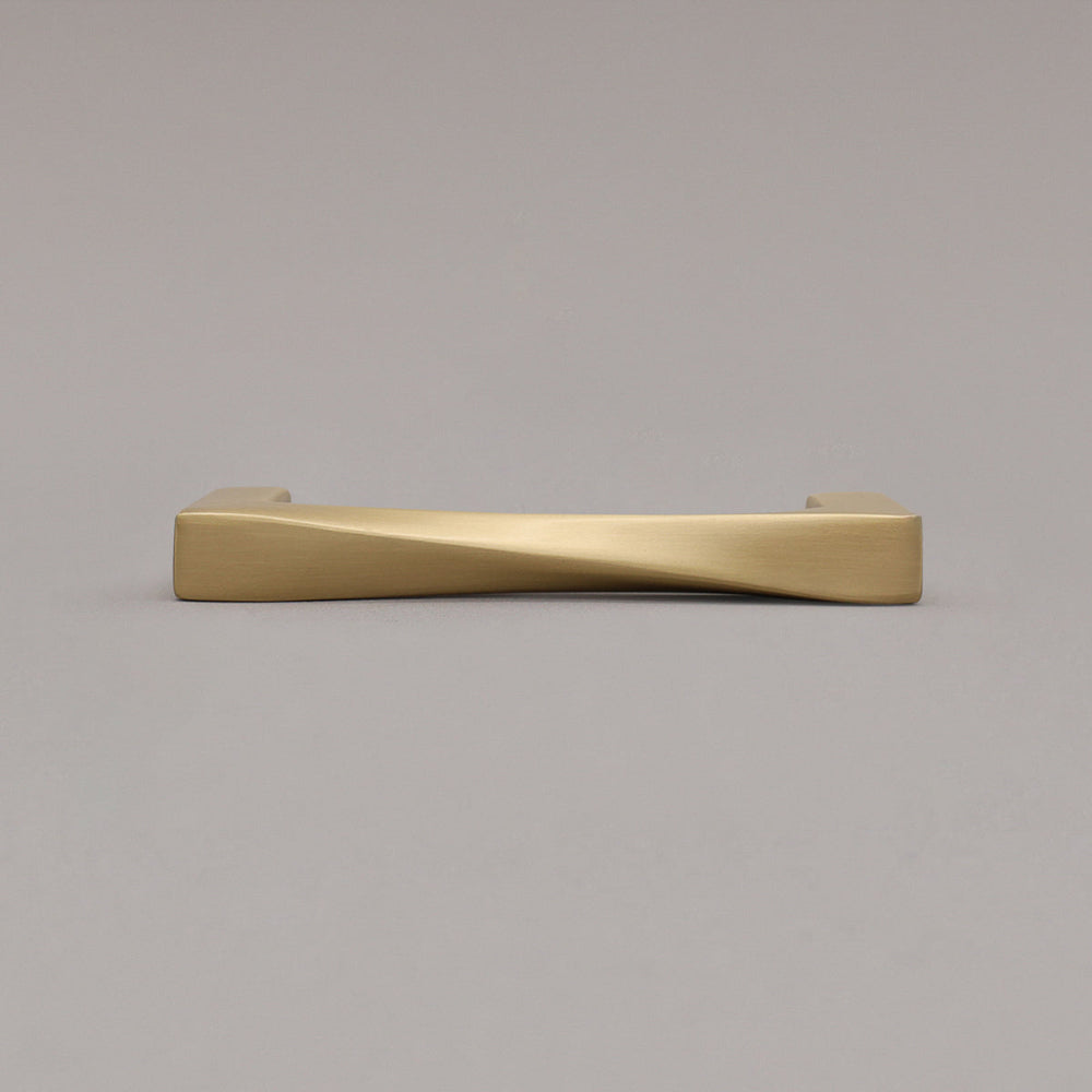 small satin brass gold twist pull laying down on gray background