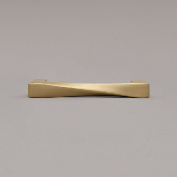 small satin brass gold twist pull laying down on gray background