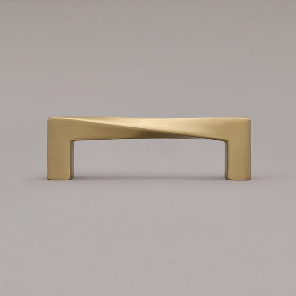 Small satin brass gold twist pull standing on gray background