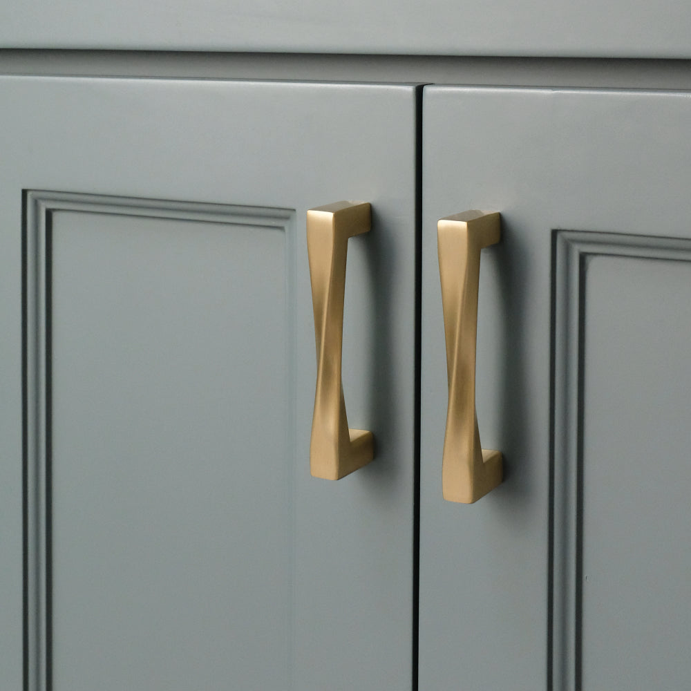 Two twist satin brass gold pulls installed on blue cabinet
