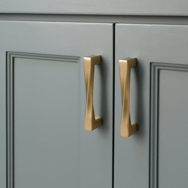 Two twist satin brass gold pulls installed on blue cabinet