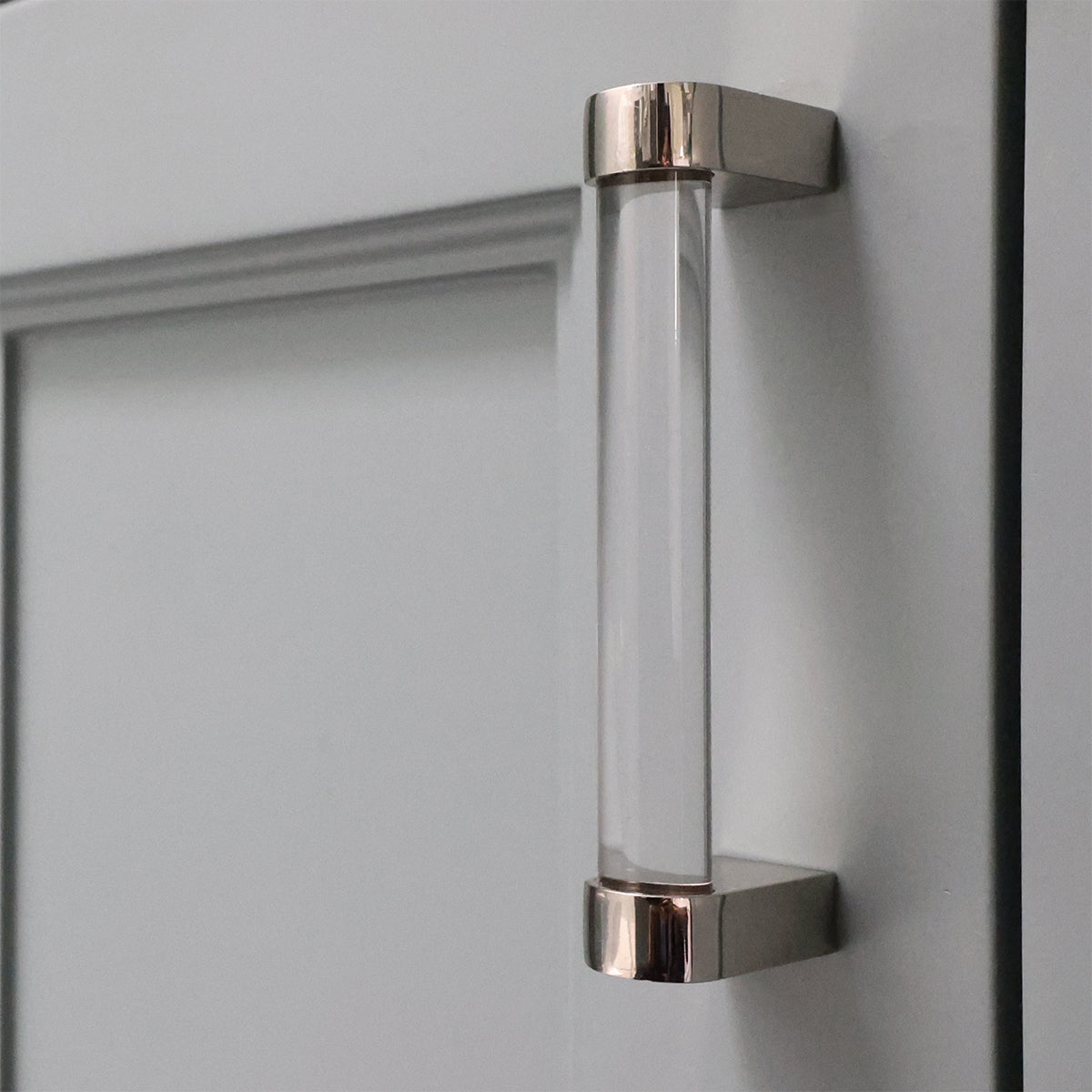 Clear glass cabinet handle with metallic finish on a gray cabinet door