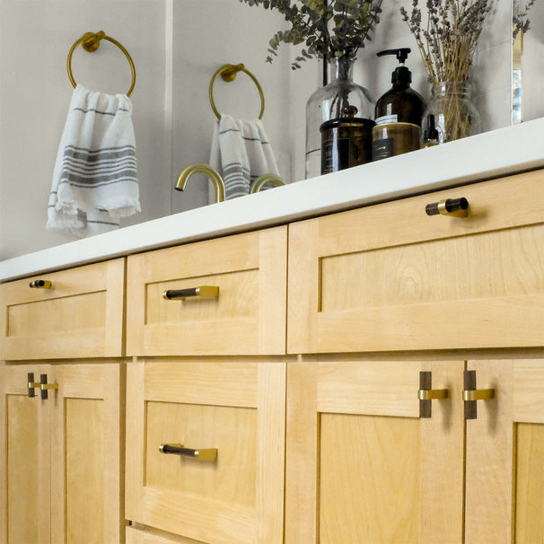 Wood Bathroom vanity with satin brass and black two tone cabinet knobs and pulls.