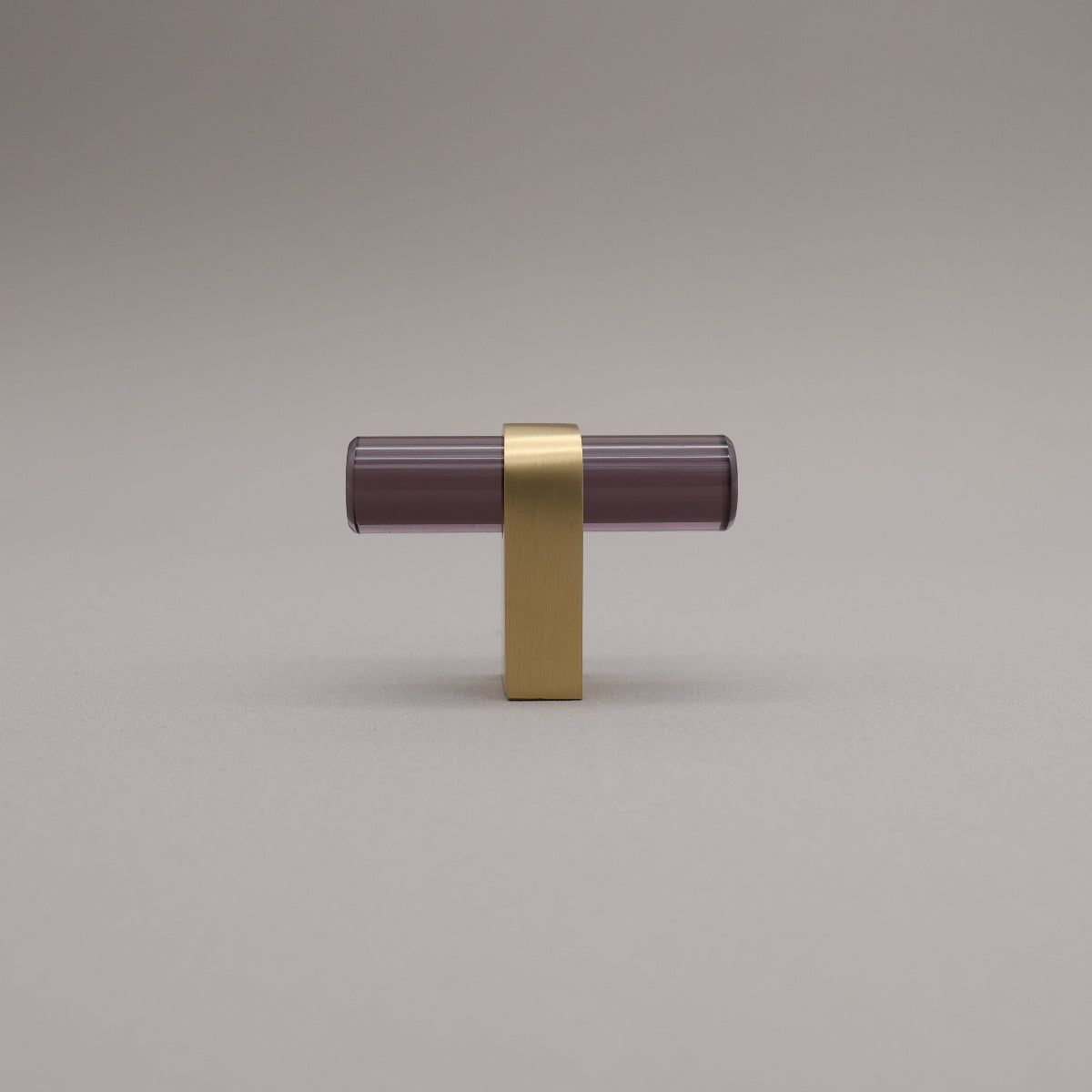 Smoke acrylic and satin brass stem knob on gray background