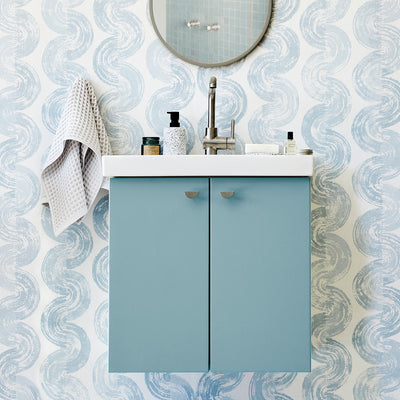 Blue bathroom vanity with towel, soap, mirror, and satin nickel half moon knobs.