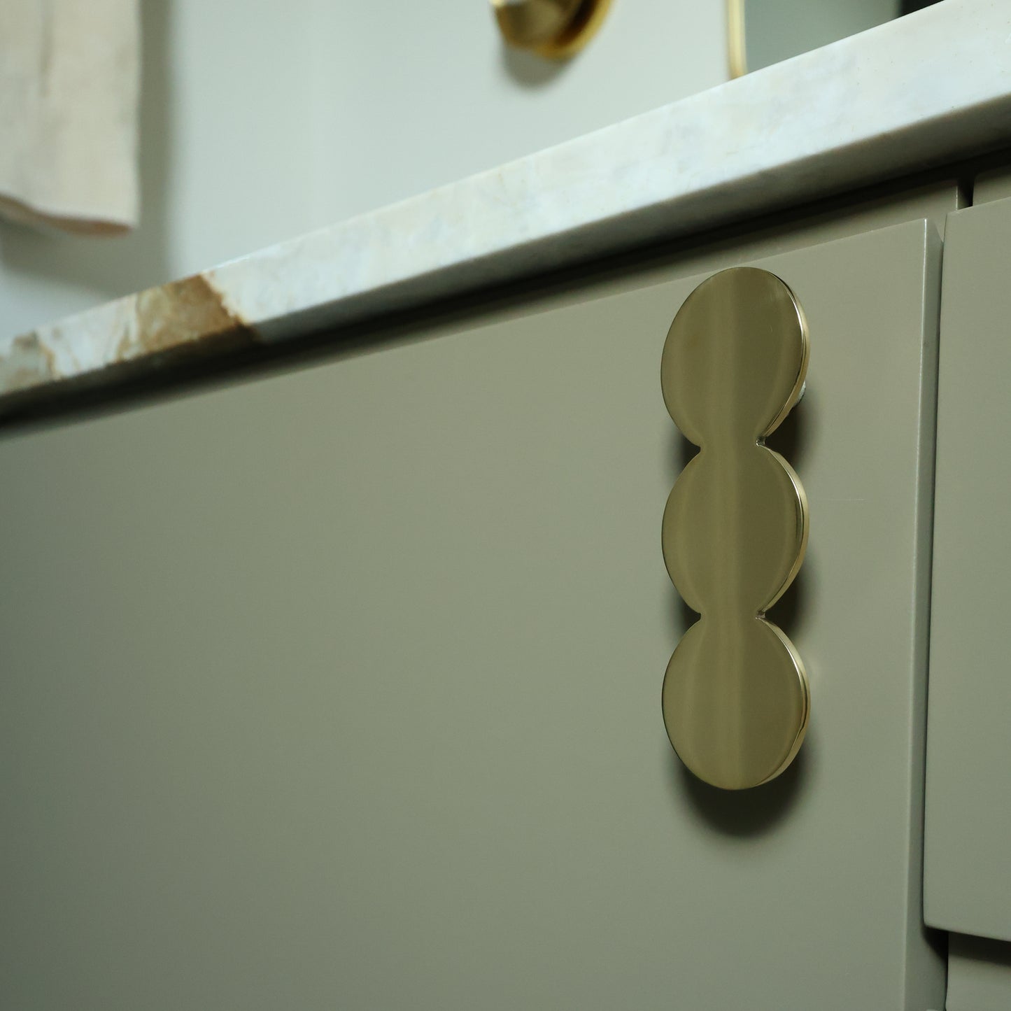 Close-up of a kitchen cabinet with unlacquered solid brass handles on a light-colored countertop.