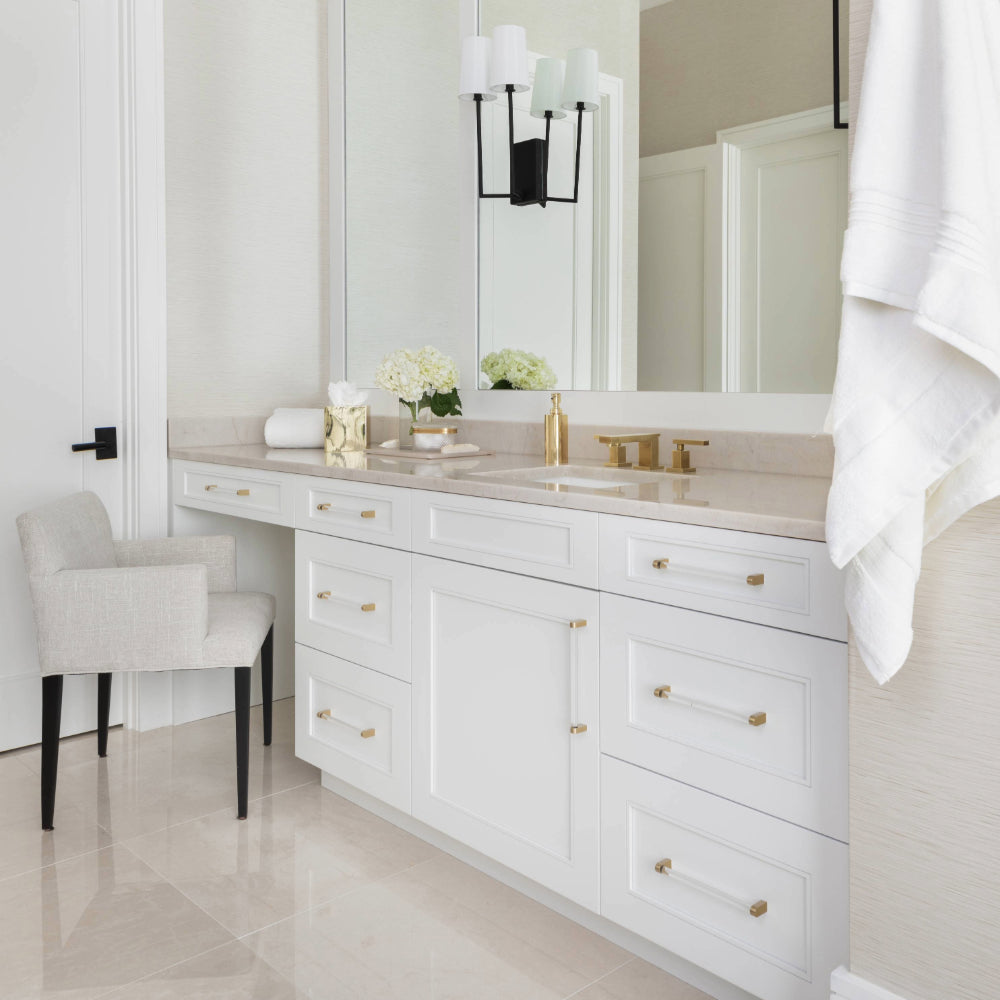 clarity satin brass cabinet pulls installed on white cabinets in bathroom