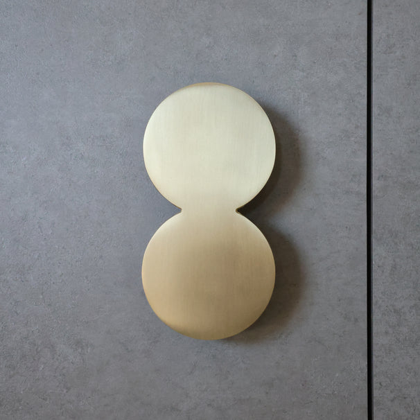 Satin Brass Cabinet Pull on a Concrete Door Phase.