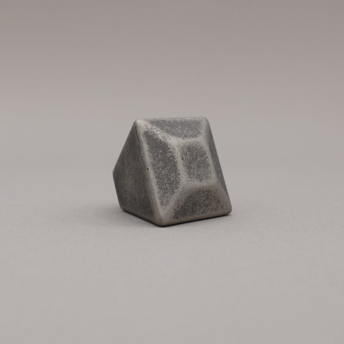 weathered distressed nickel geometric diamond knob on a gray background