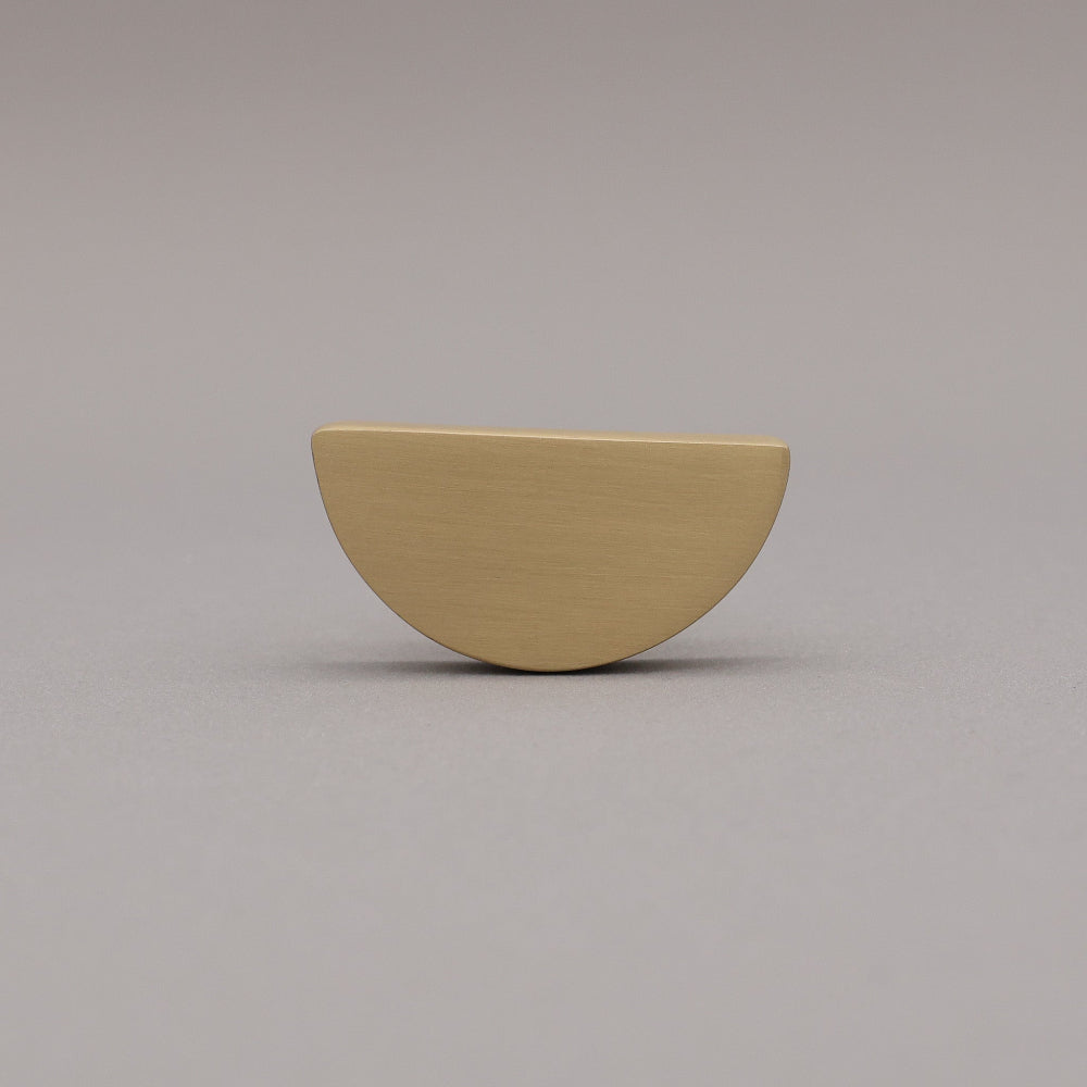 satin brass gold half-circle half moon cabinet knob on gray background