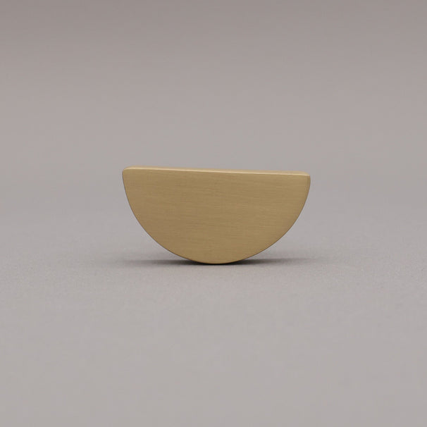 satin brass gold half-circle half moon cabinet knob on gray background