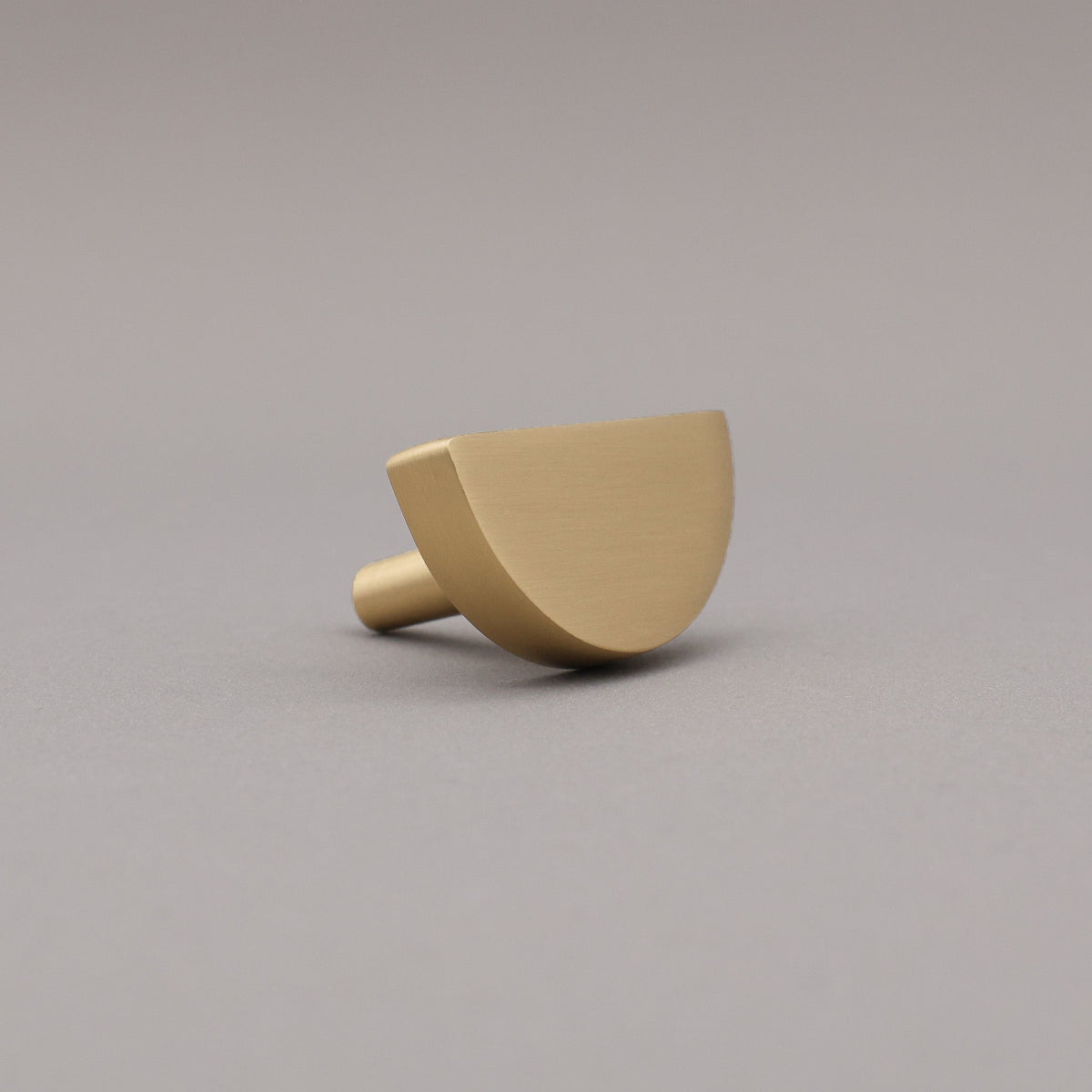 satin brass gold half moon knob on gray background