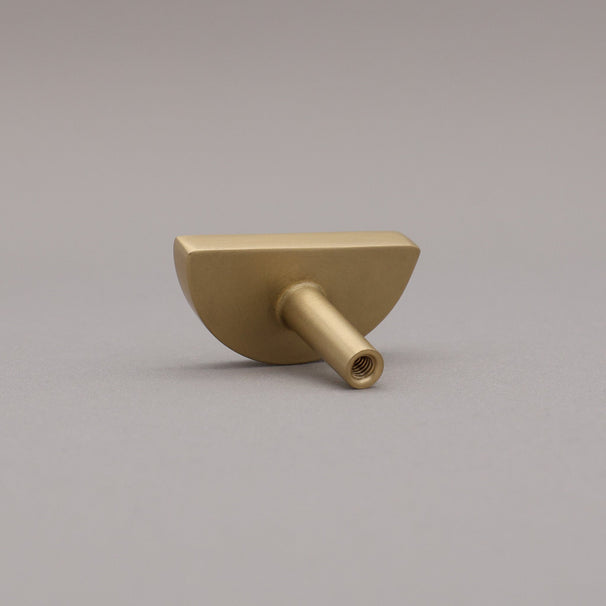 satin brass gold half-circle half moon cabinet knob on gray background