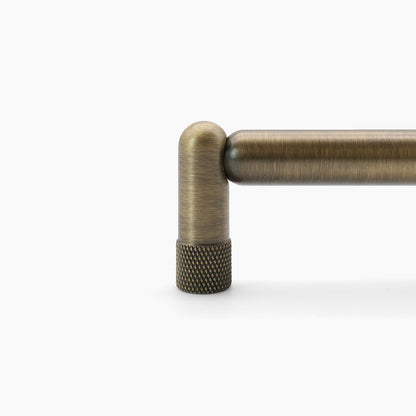 Aged brass knurled stem detailing on cabinet pull.