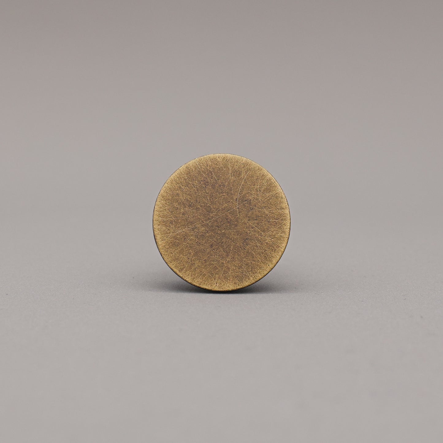 Round brass object on a gray background
