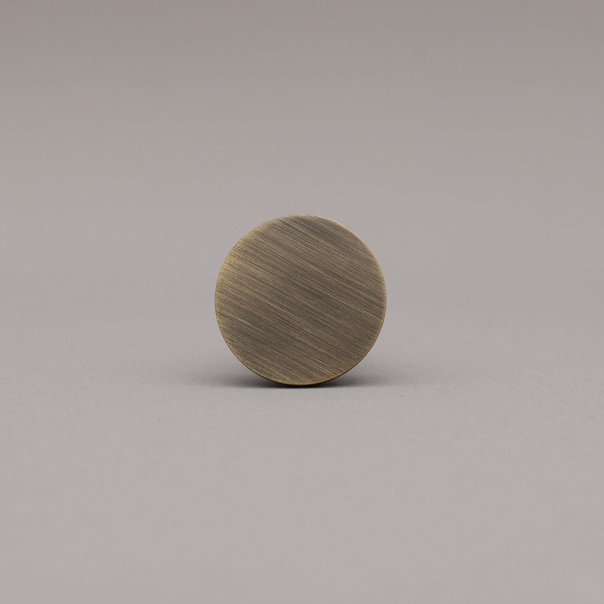 Round aged brass cabinet knob face on a gray background