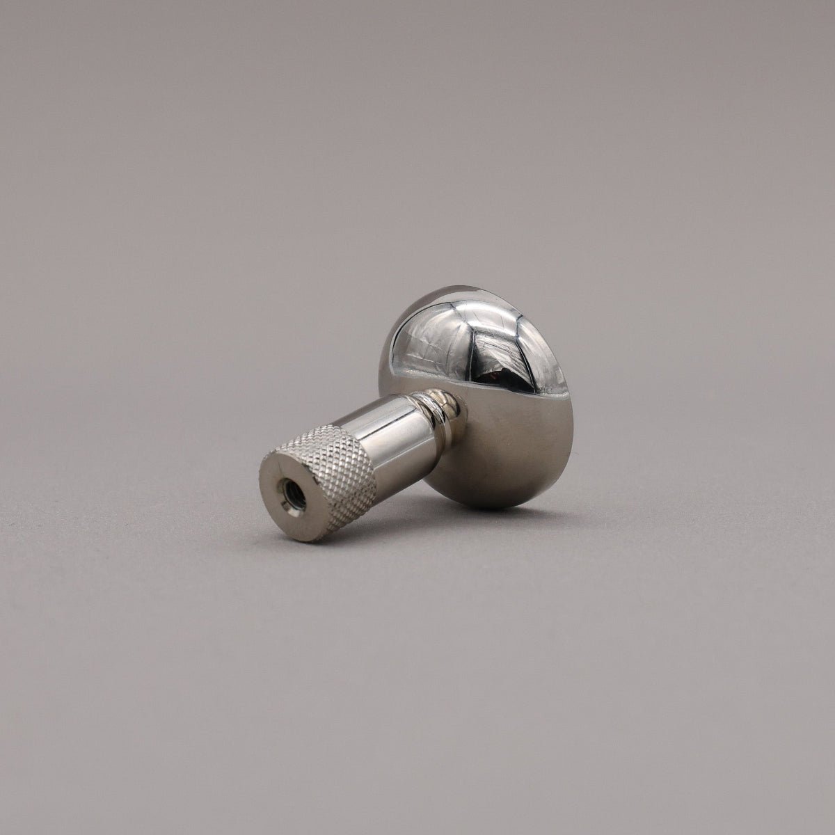 Polished nickel finished knurled cabinet knob on a gray background