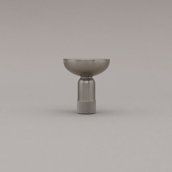 Skinny knurled knob in satin nickel finish standing upright on grey background. 