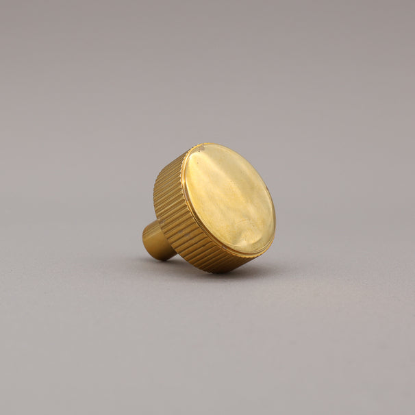 unlacquered polished brass gold textured ribbed knob with fluting detail on a gray background