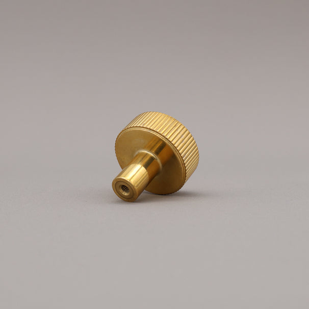 unlacquered polished brass gold textured ribbed knob with fluting detail on a gray background