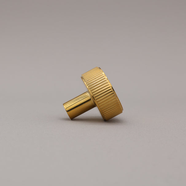 unlacquered polished brass gold textured ribbed knob with fluting detail on a gray background