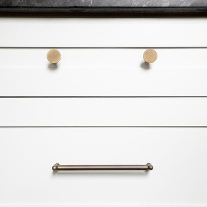 Close-up of white drawers with antique english knobs and an antique english handle.