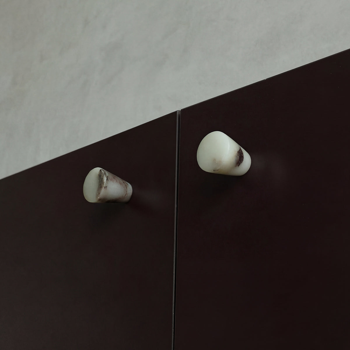 Marble knobs finished in a Calacatta Viola on Burgundy cabinets.