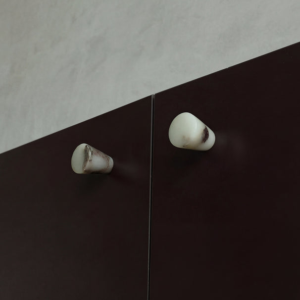 Marble knobs finished in a Calacatta Viola on Burgundy cabinets.