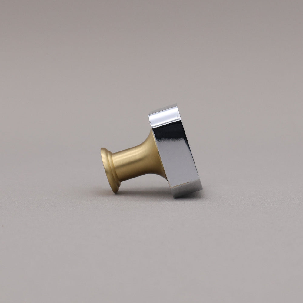 Polished chrome and brass gold square knob on a gray background