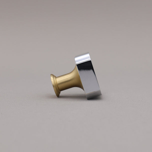 Polished chrome and brass gold square knob on a gray background