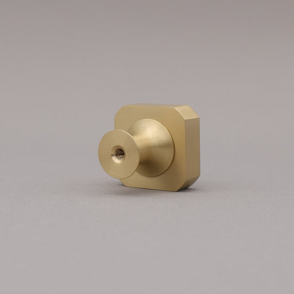 Satin brass gold square knob on gray background