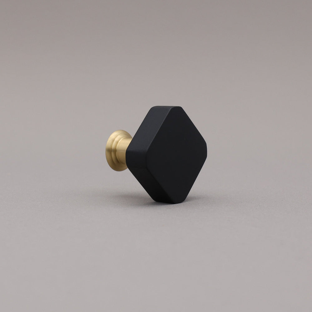 Black and brass gold square knob on a gray background