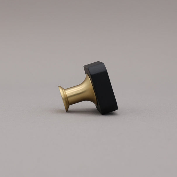 Black and brass gold square knob on a gray background