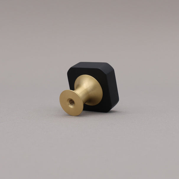 Mod black and satin brass two tone knob on a gray background, rear view