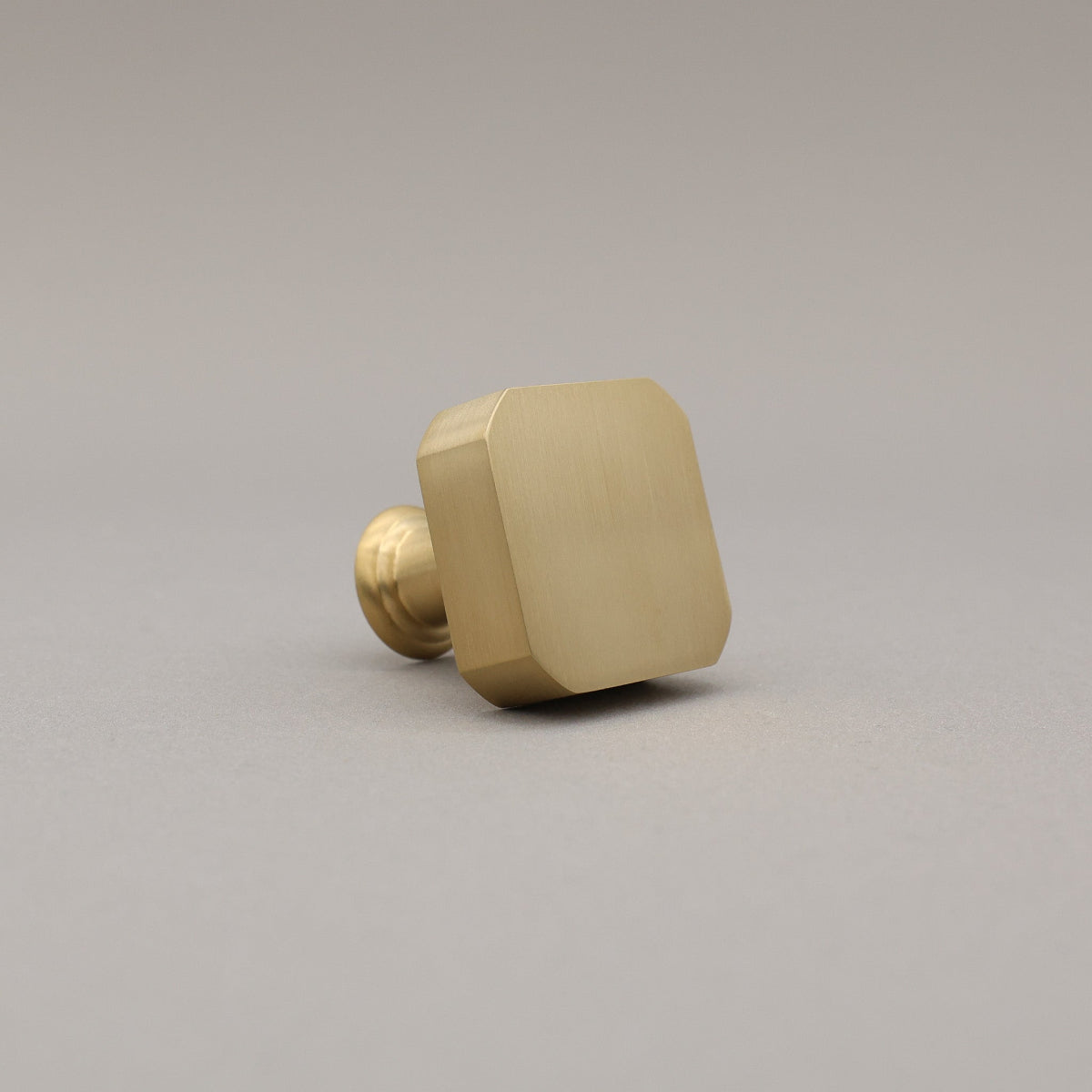 unlacquered satin brass gold square mod knob on gray background