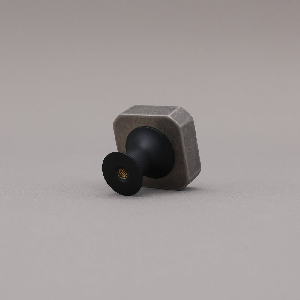 Weathered nickel and matte black two tone square knob on gray background