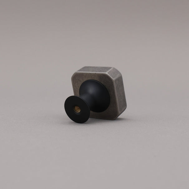 Weathered nickel and matte black two tone square knob on gray background
