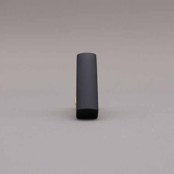 Front satin brass and black t-knob brass cabinet knob on gray background.