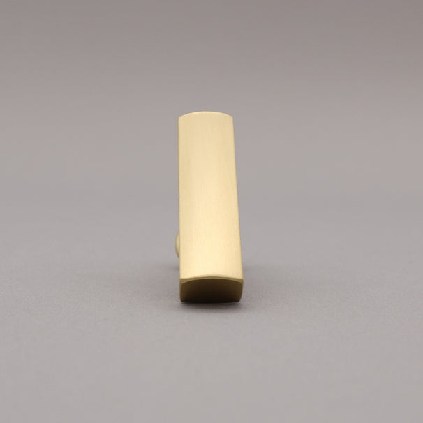 Front leaning satin brass t-knob brass cabinet knob on gray background.